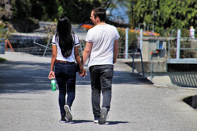 Žena a muž, pár sa drží za ruku, kráča po ulici