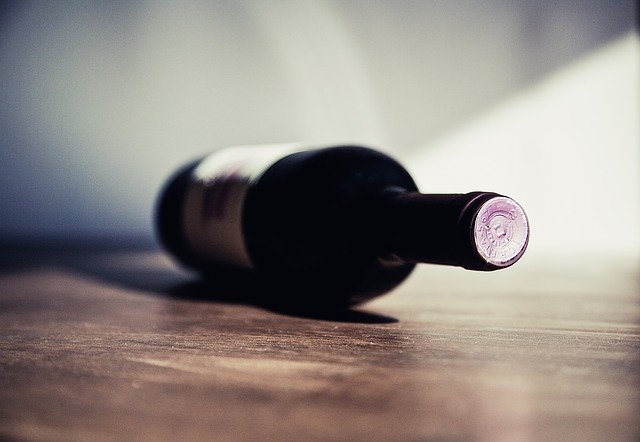 Fľaša vína leží na drevenom stole.jpg